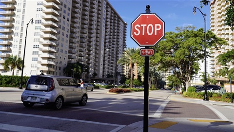Stop sign and car on road between condo buildings.