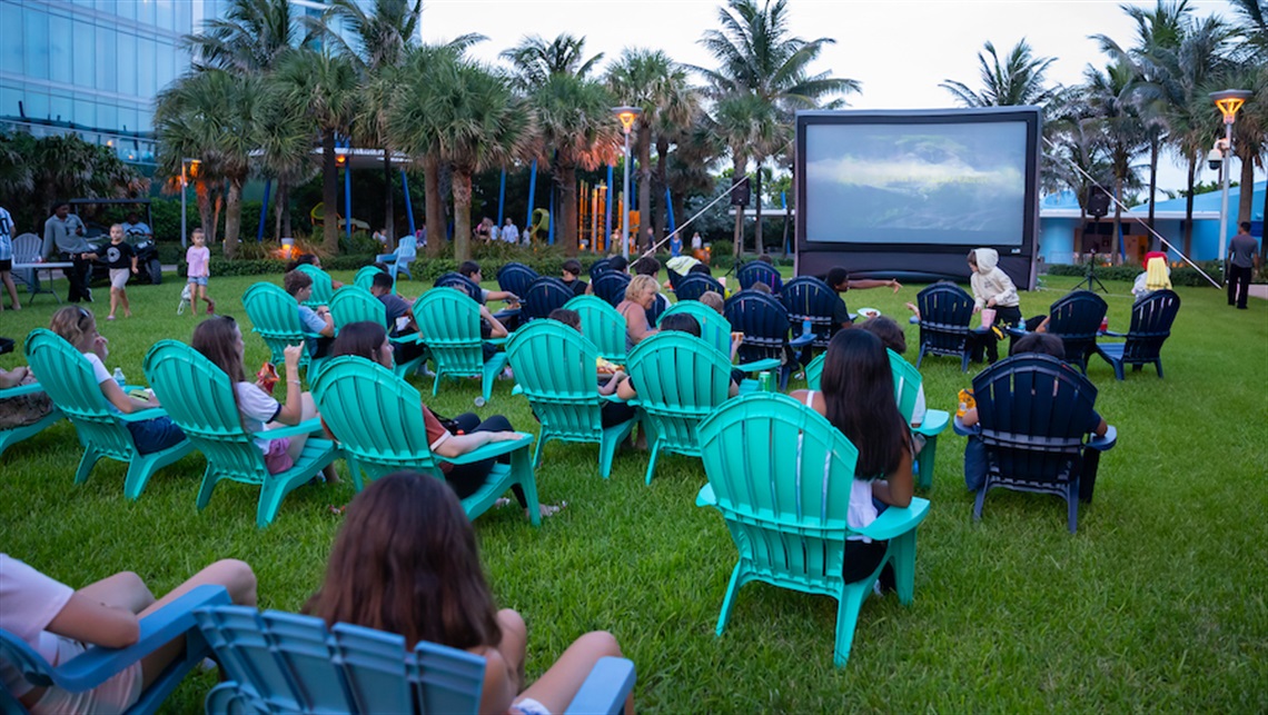 Families watching a movie in Samson Oceanfront Park on lawn chairs. 