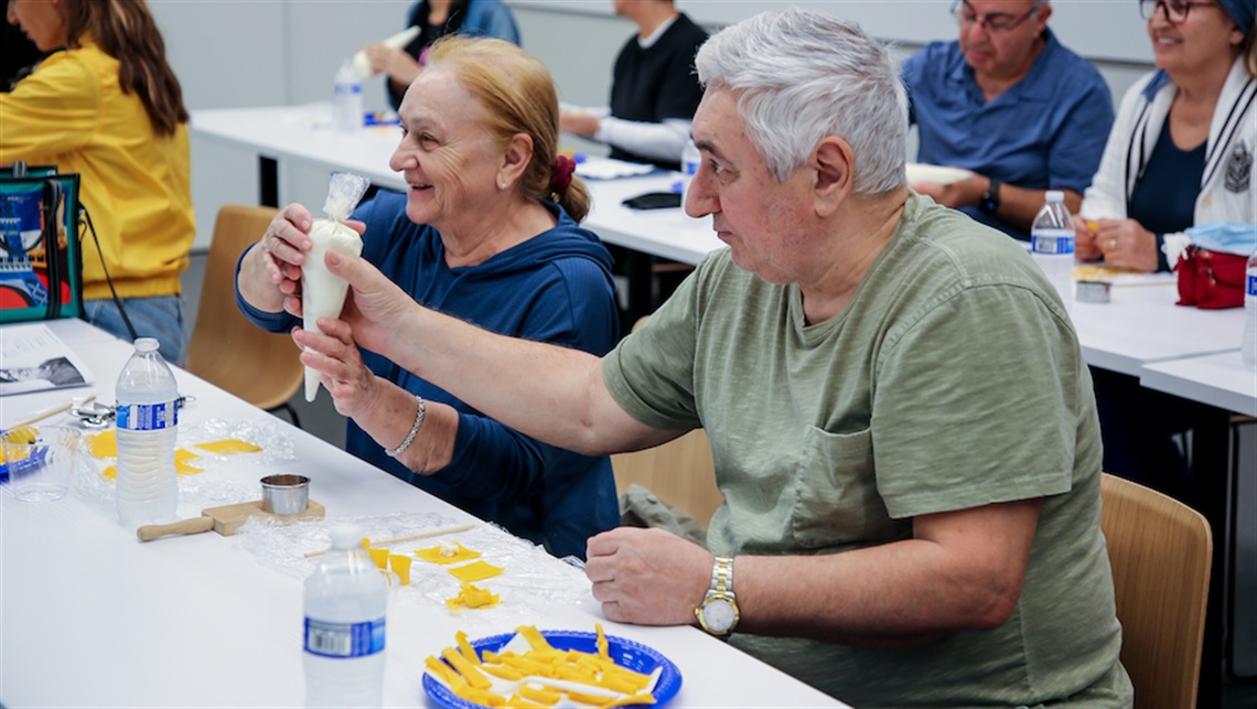 Couple making pasta while sitting at table at a Cooking Workshop